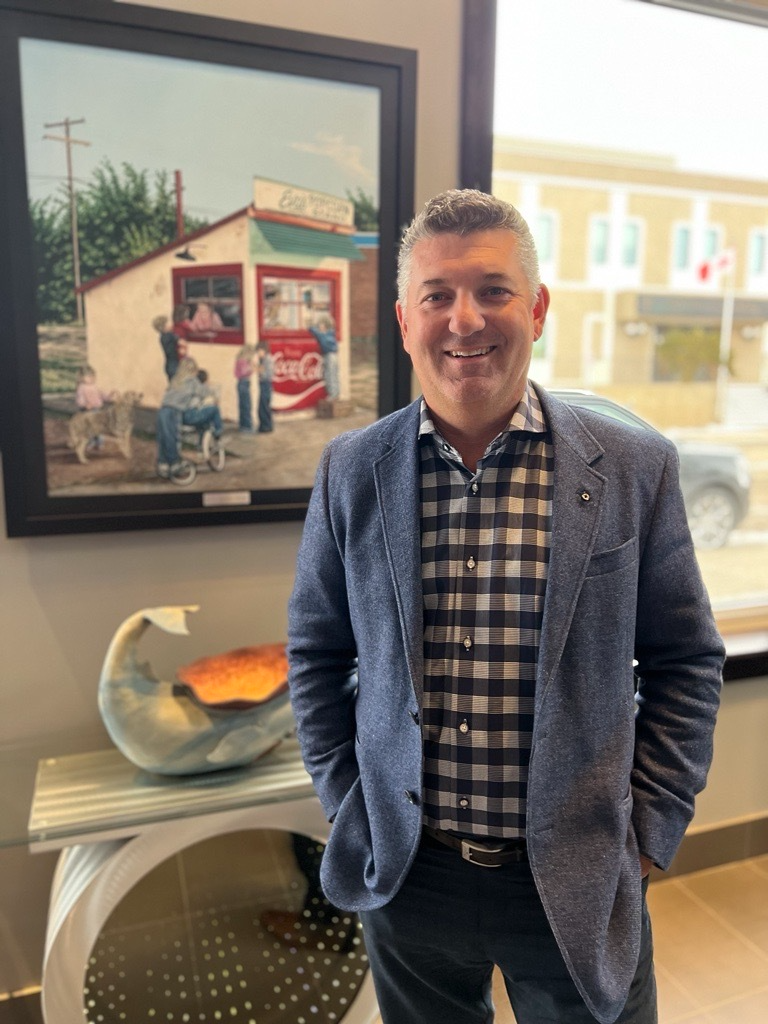 Joseph smiling and standing in front of a picture on the wall