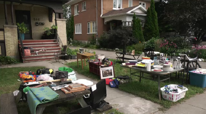Front view of a house with furniture and other items laid out on the lawn.