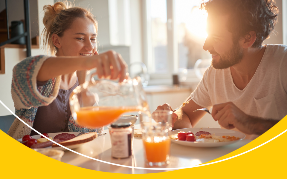 Daughter pouring a glass of orange juice for her father