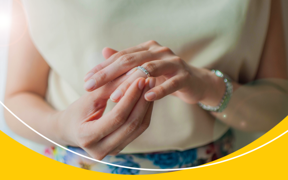 A lady is taking a wedding ring off of her finger