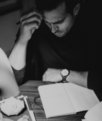 A man thinking at his desk with a planner in hand