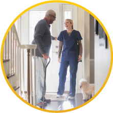 A nurse with her patient who is holding a walking stick