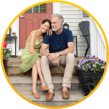 an elderly couple sitting in the front porch on the steps and smiling