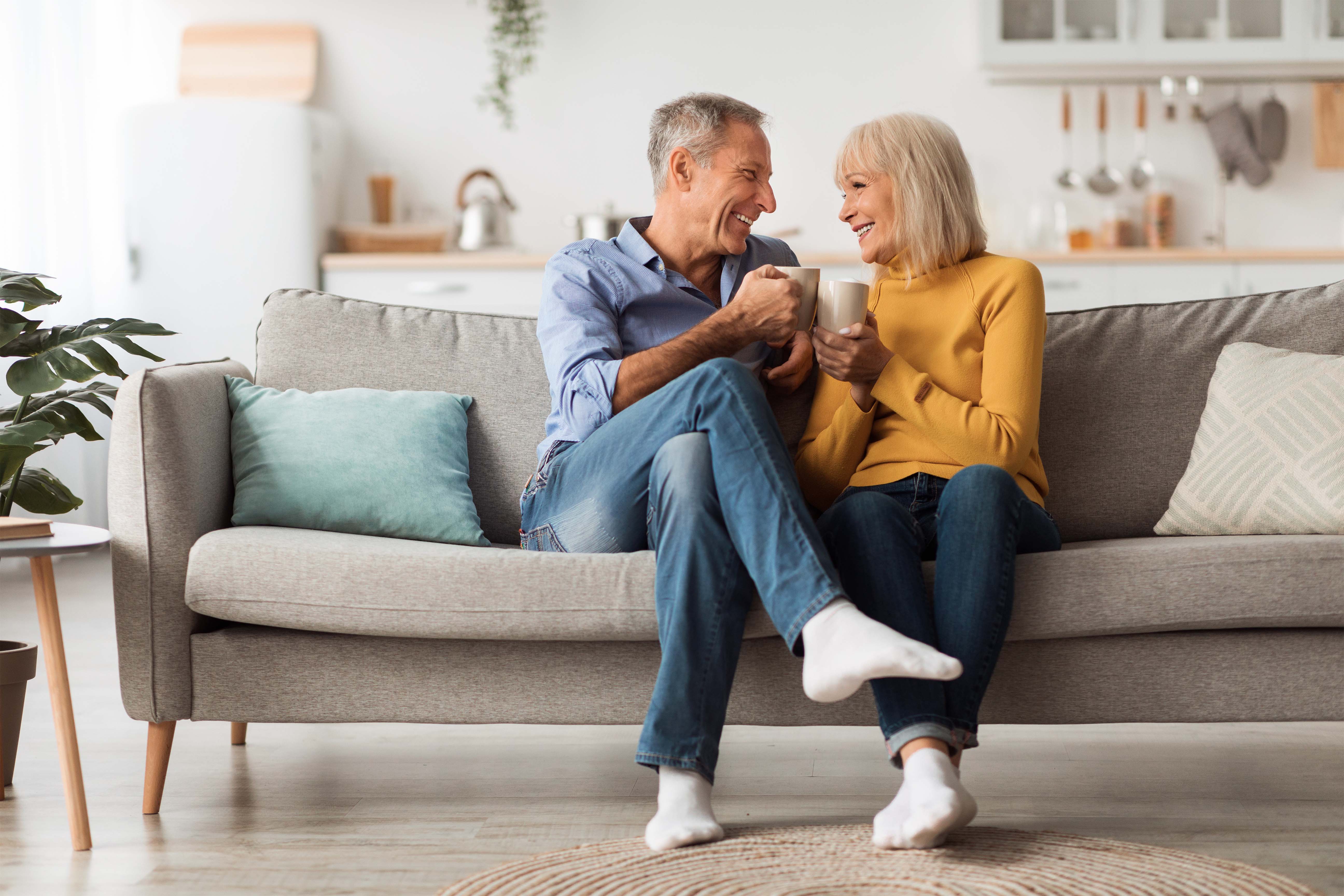 An elderly couple sitting on a couch and enjoying coffee