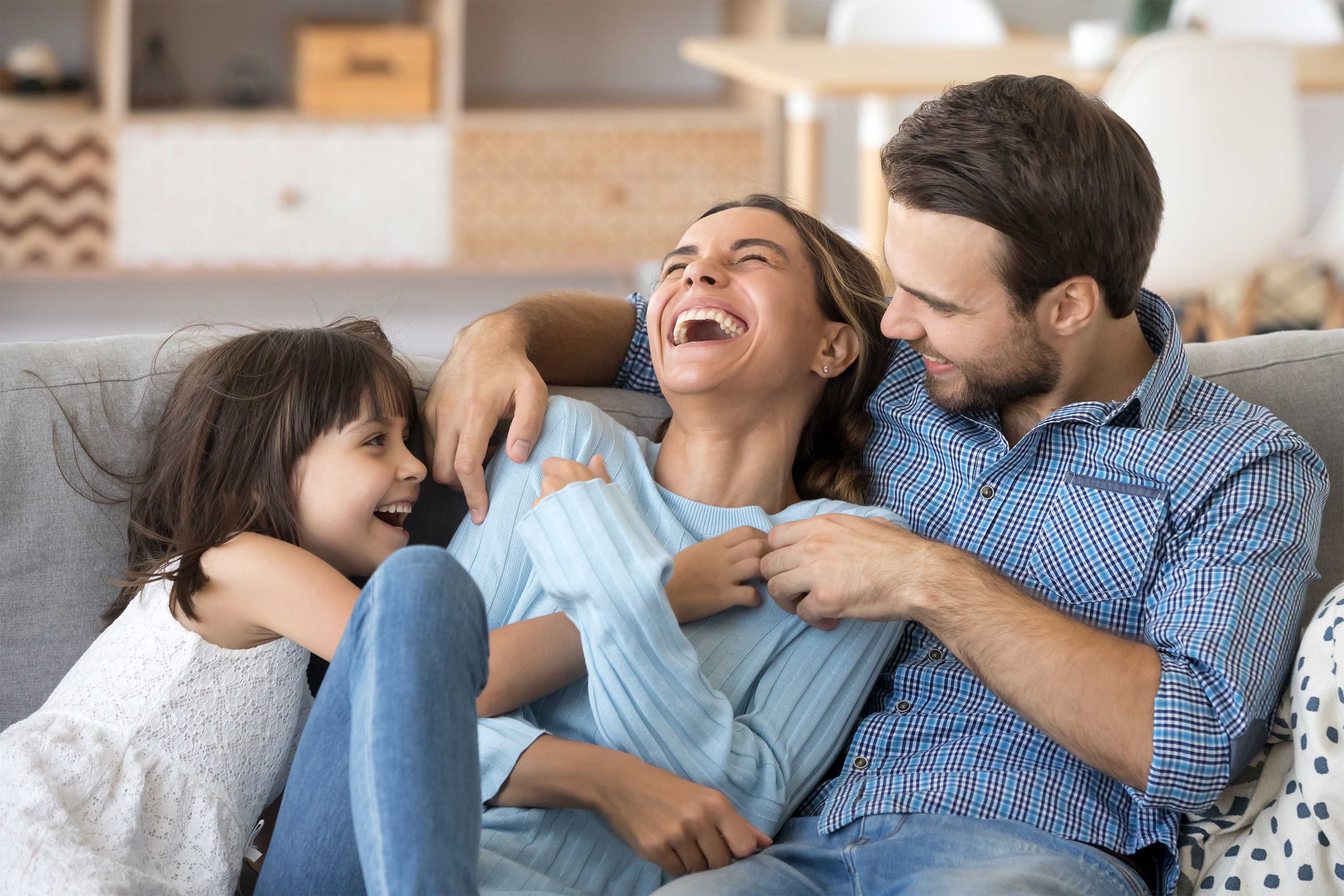 Mother and father sharing a laugh with their daughter on a couch