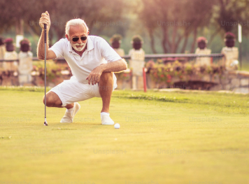 Older gentlemen squatting down to view a golf ball on the field