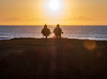 A couple sitting on the beach watching the Sun set