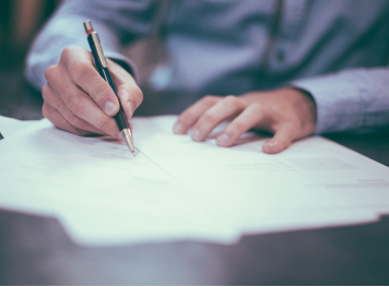 Wide angle view of a person drawing a line carefully on paper with a pen