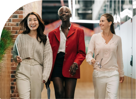 three young business women walking in a row smiling and looking at each other.